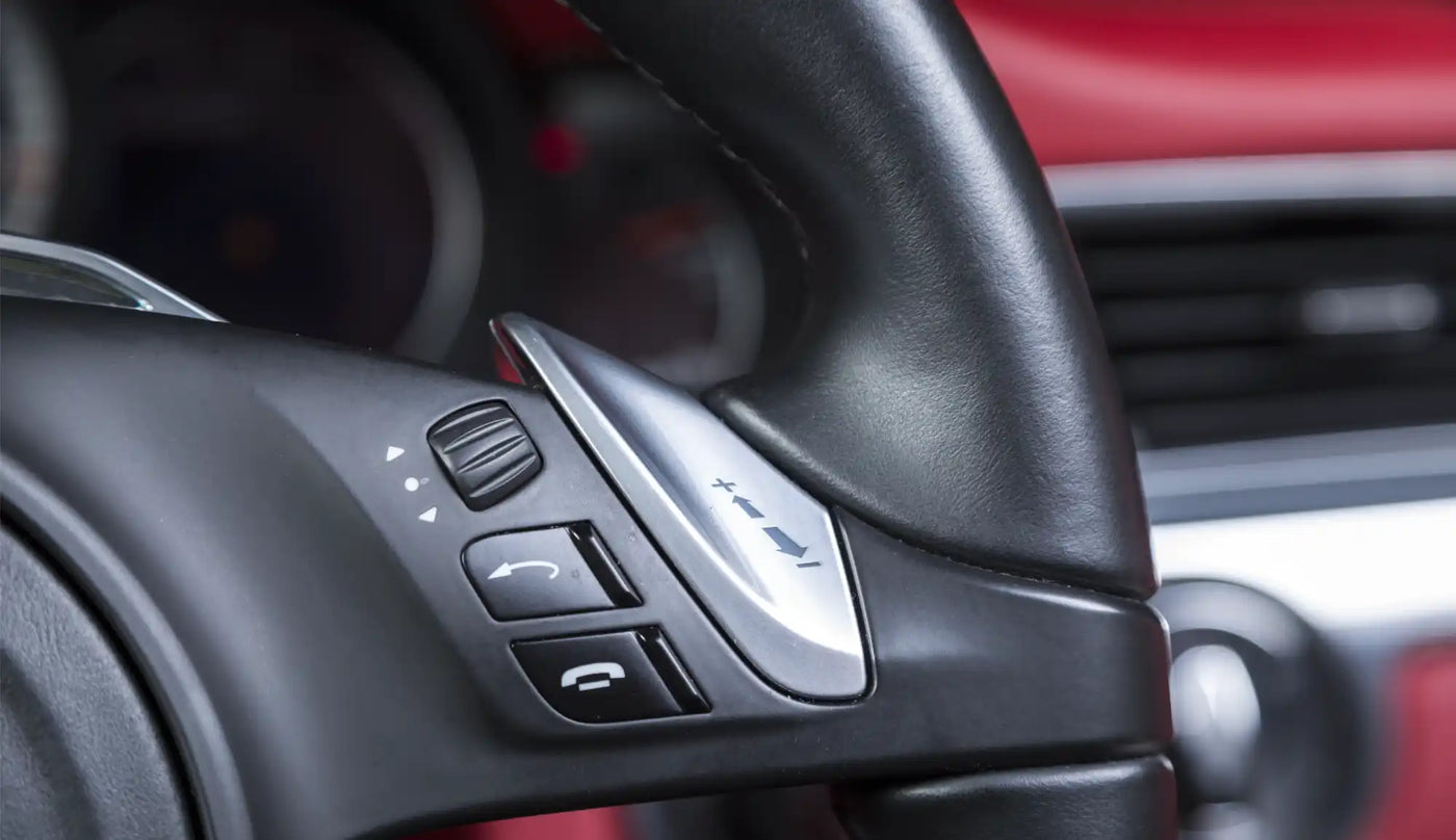 Black leather-wrapped steering wheel with mounted control buttons.