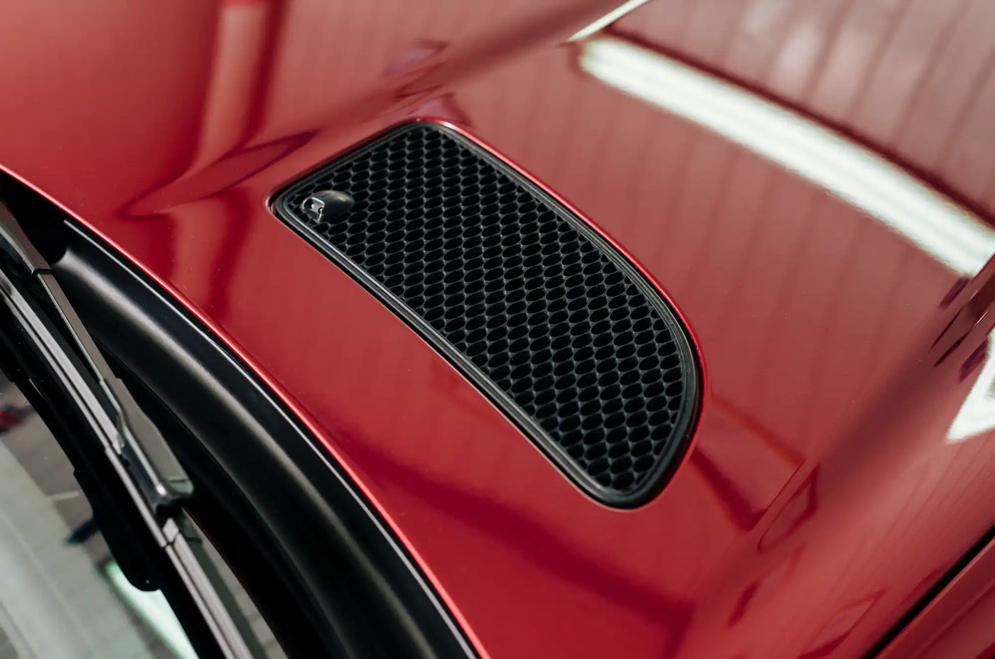 Hood scoop vent on a glossy red car.